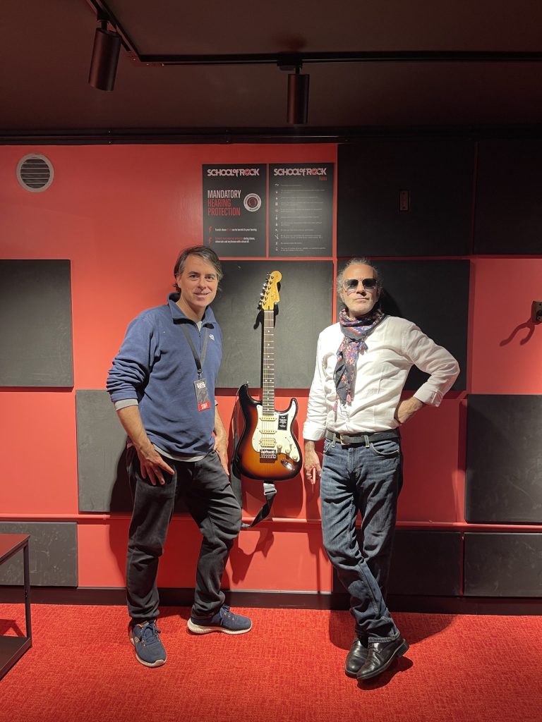 Two men pose next to an electric guitar in the recently opened school of rock branch in Twickenham.