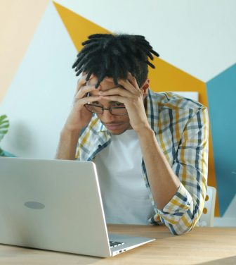 Frustrated young man sat at laptop.