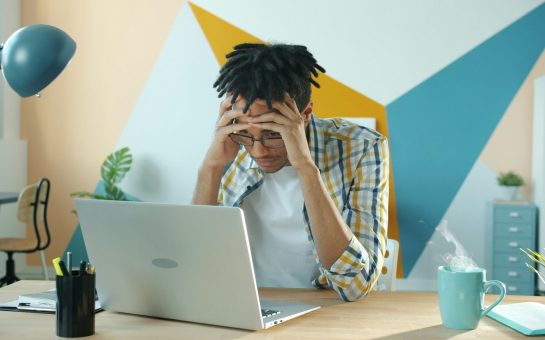 Frustrated young man sat at laptop.