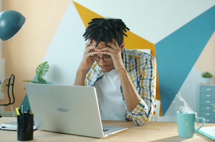 Frustrated young man sat at laptop.