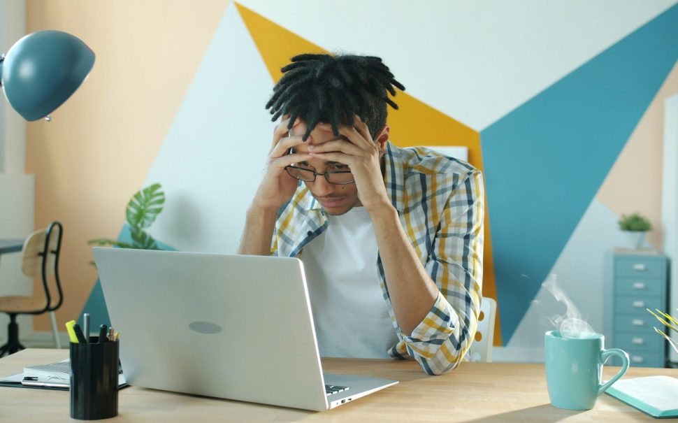 Frustrated young man sat at laptop.