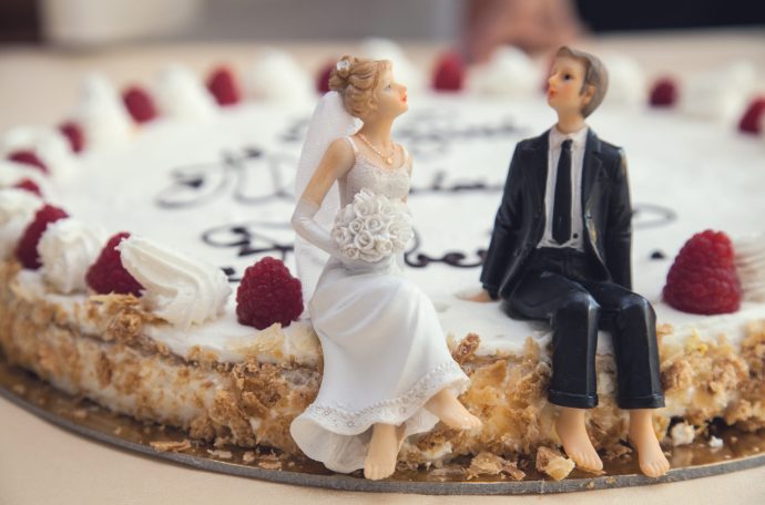 Model couple sat on top of wedding cake