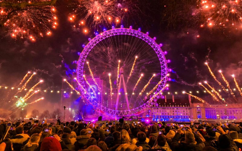 A large crowd looking at fireworks over the London Eye