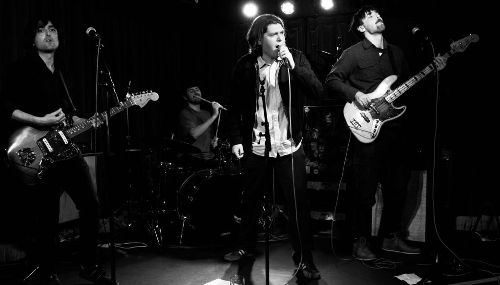 Three men on stage on a band performing a song