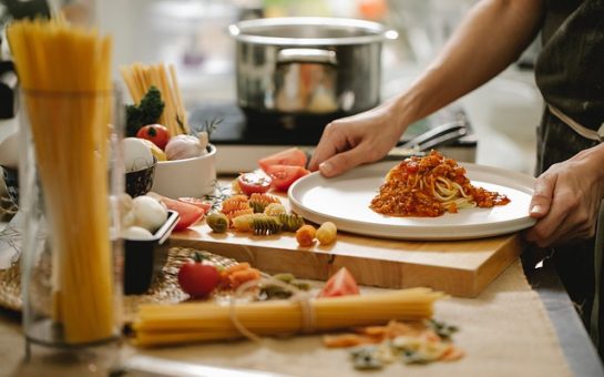 A person making Italian food, with ingredients lying on the table