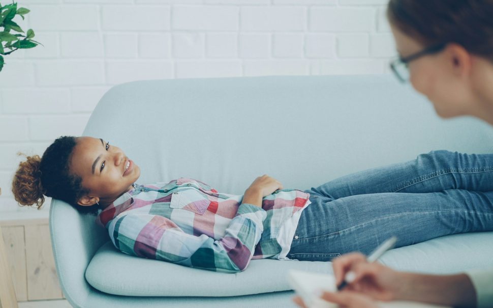 Teenager lies on sofa in discussion with her councillor