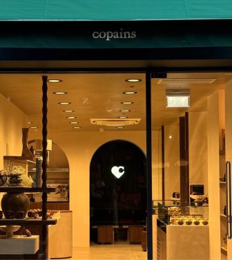 Copains London bakery storefront green canopy with business name and warm bakery interior