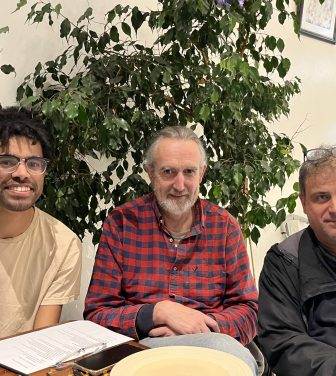 Three men sit at a table
