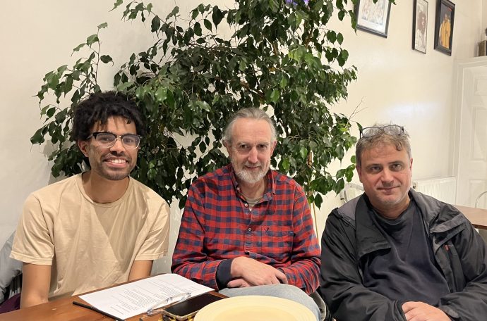 Three men sit at a table