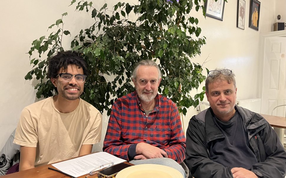 Three men sit at a table