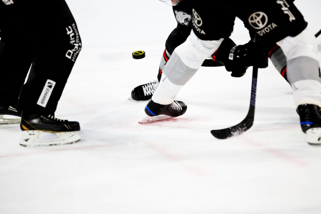 Image of ice hockey players legs and feet playing on the ice rink with a puck and an ice hockey stick