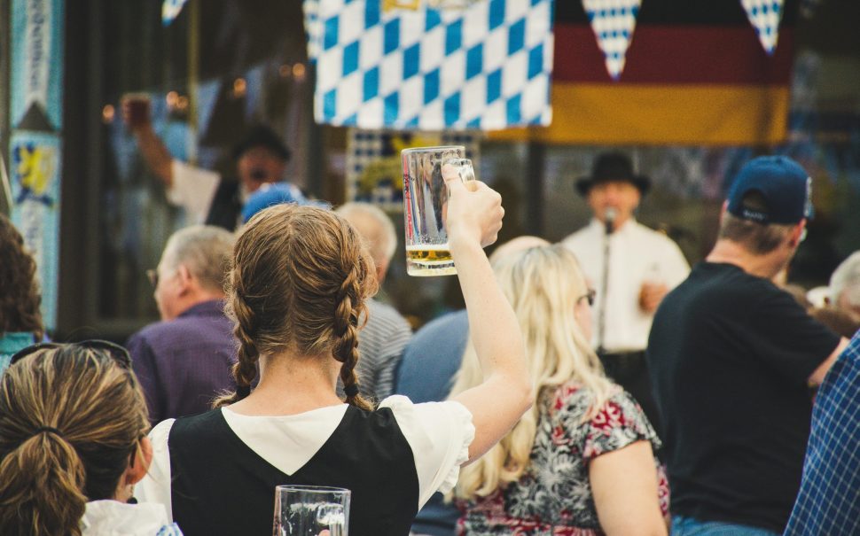 A woman lifts a beer at an Oktoberfest celebration. Credit: Brett Sayles/ Pexels.