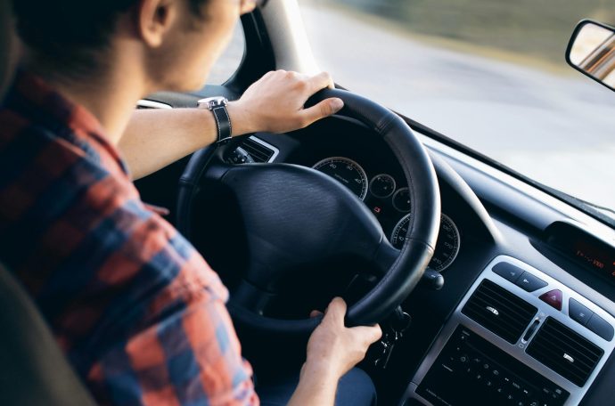 A young man sits at the steering wheel of a car