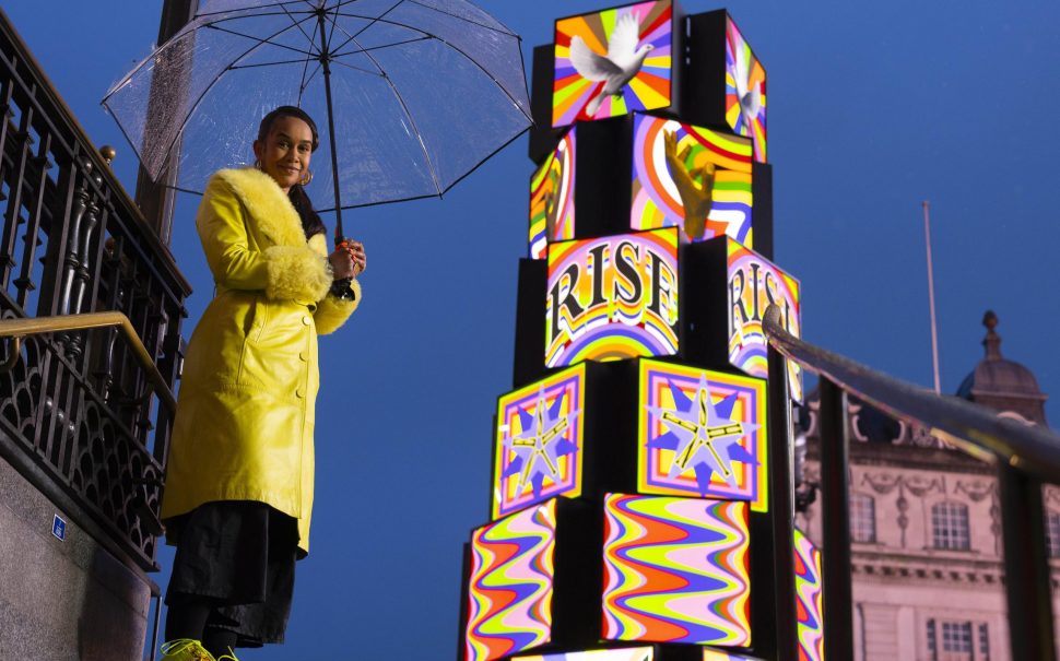 Artist Lakwena Maciver in front of her installation Rise and Shine, in Piccadilly Circus.