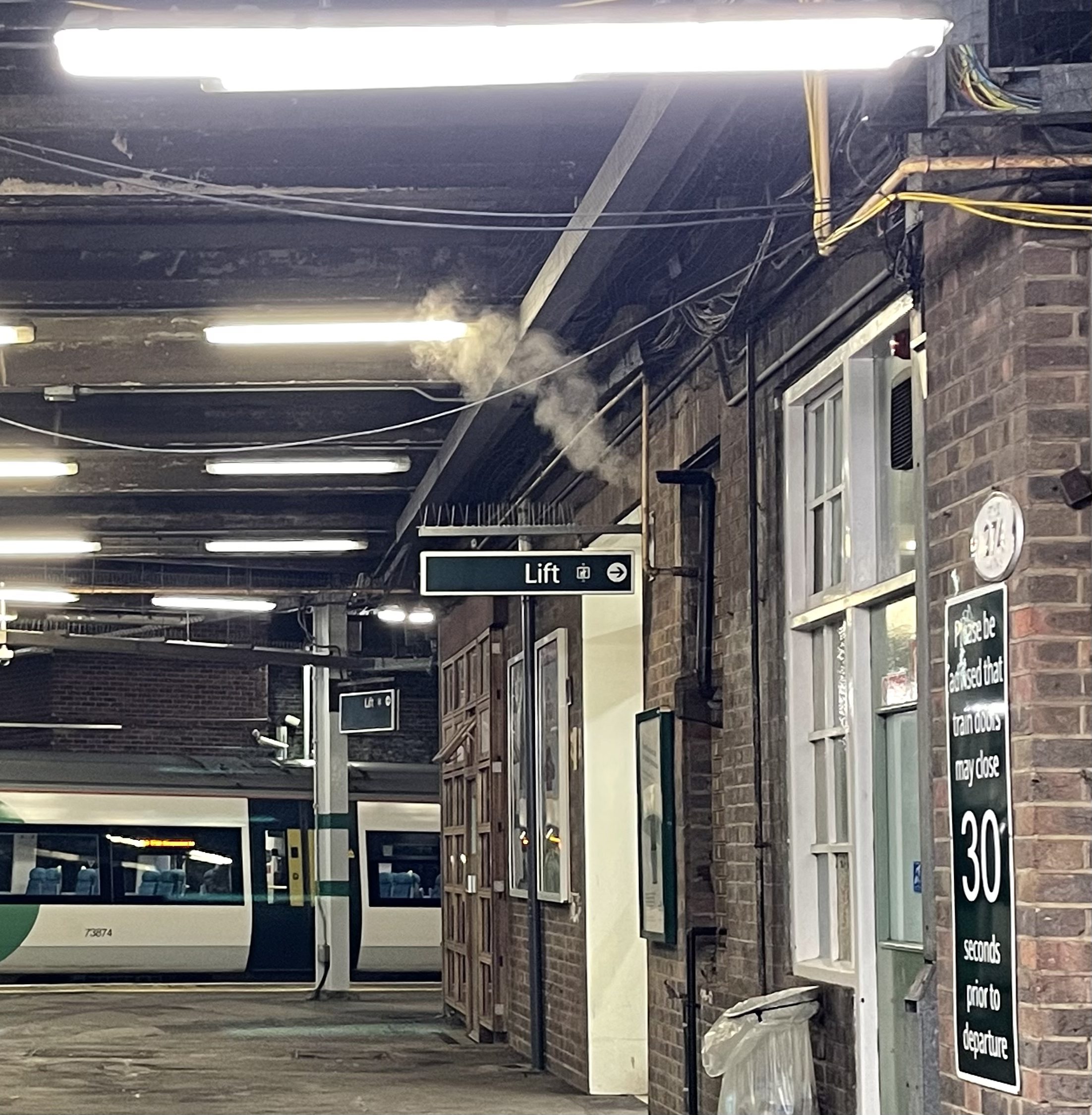 An empty platform at a train station, showing written signs to lifts and information about door closure. Image credit: Joshua Brown.