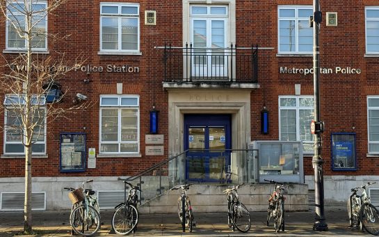 The front of Twickenham police station building - with bikes in front of it, a tree and sunshine.