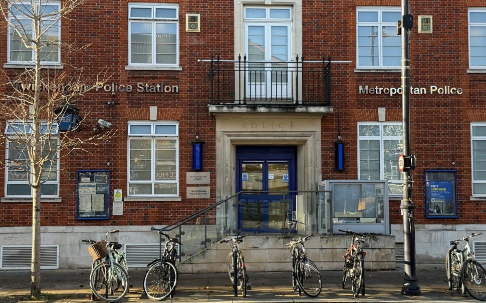 The front of Twickenham police station building - with bikes in front of it, a tree and sunshine.