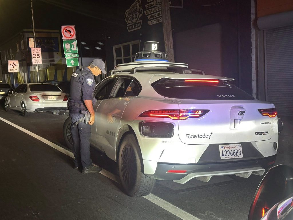 A San Bruno Police officer looks into the driverless-window of a Waymo vehicle he has pulled over in San Fransisco, United States. 