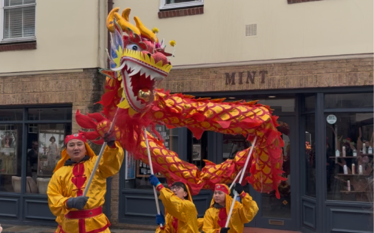 Dragon dancers dressed in red and yellow holding a red Chinese dragon