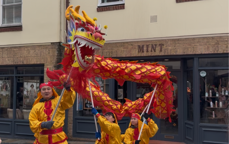 Dragon dancers dressed in red and yellow holding a red Chinese dragon