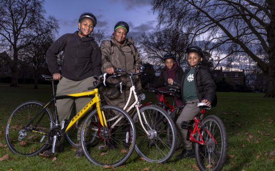 A family stand in the park with their bikes.