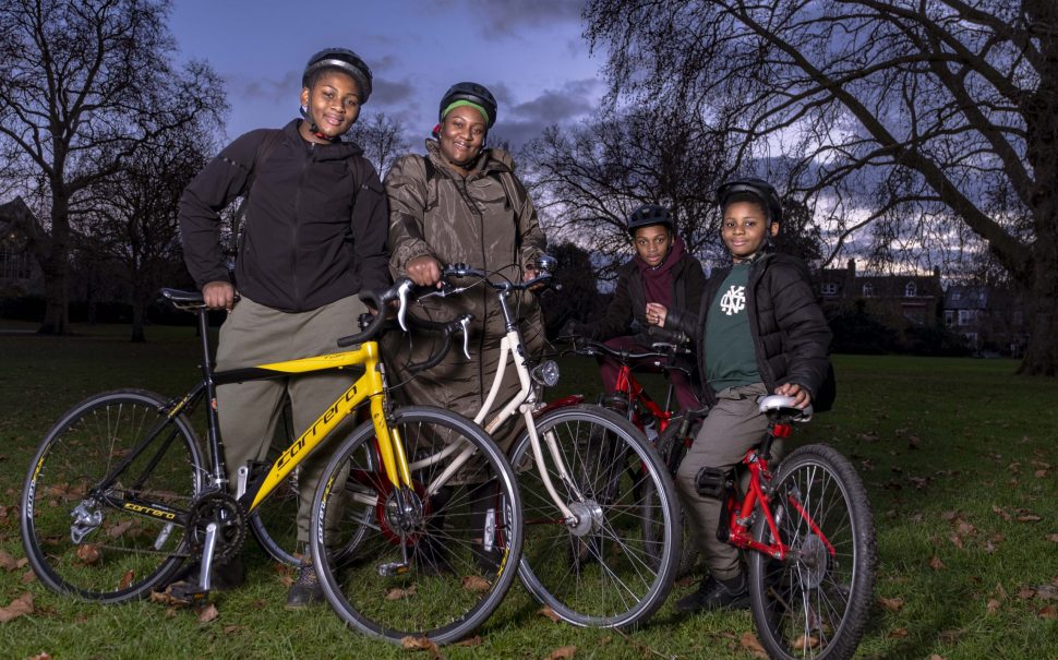 A family stand in the park with their bikes.