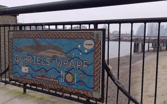 A mosaic sign for Gabriel's Wharf, on London's South Bank. Towers in the City of London can be seen in the distance.