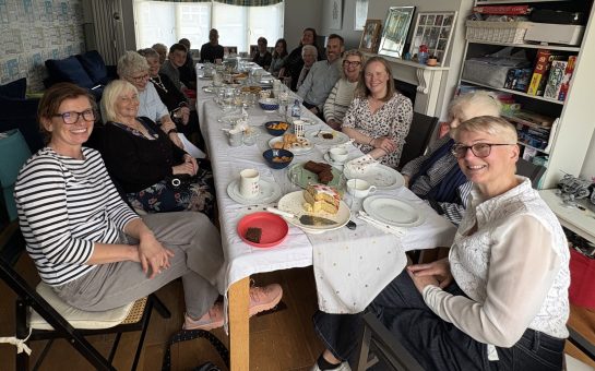 Group of people sat around a table enjoying a tea party.