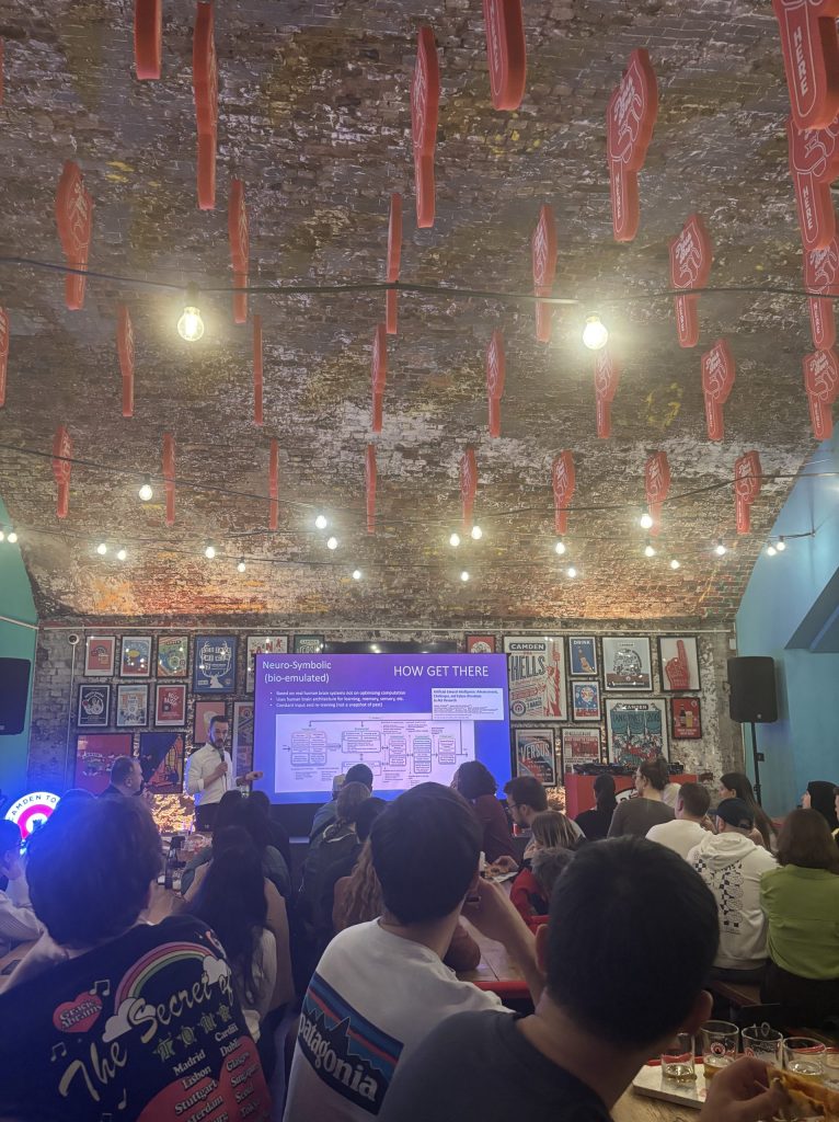 People in a pub watching an academic lecture on a big screen.