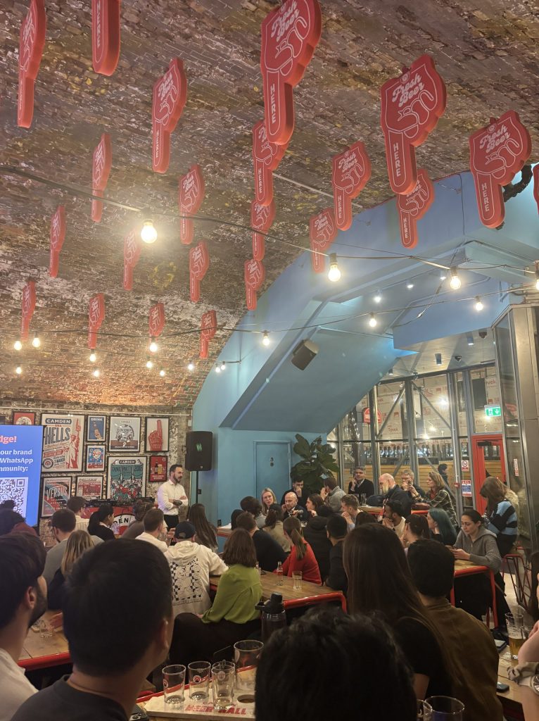 A crowd in a pub asking questions to a lecturer.