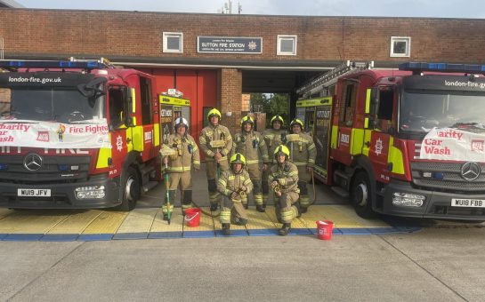 Firefighters in full kit outside Sutton fire station with two fire trucks promoting the fire fighters charity car wash