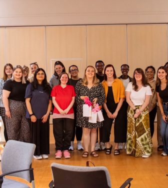 Group of people standing facing the camera in a hall.