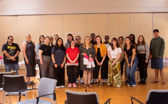 Group of people standing facing the camera in a hall.