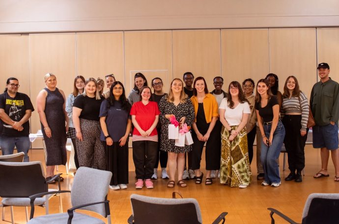 Group of people standing facing the camera in a hall.