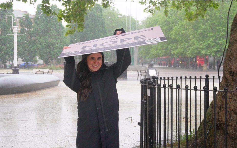A Refuge campaigner shields herself from the torrential rain with her large 'Hope' sign.