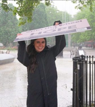 A Refuge campaigner shields herself from the torrential rain with her large 'Hope' sign.