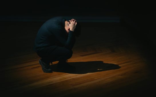 Man crouches over symbolising suicide.
