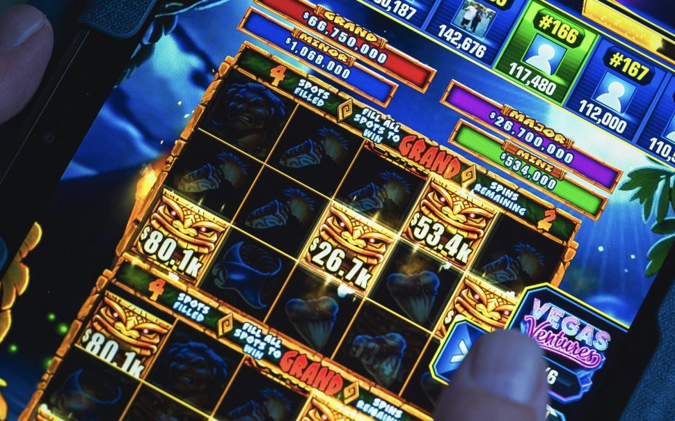 A close up image of a person playing a colourful online casino game on a tablet.