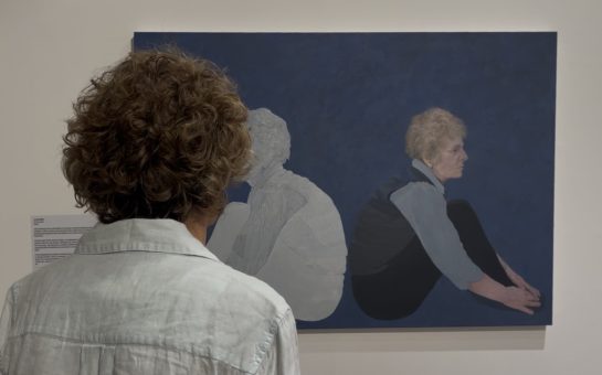 Artist Lucy ash admires her central portrait at the exhibition