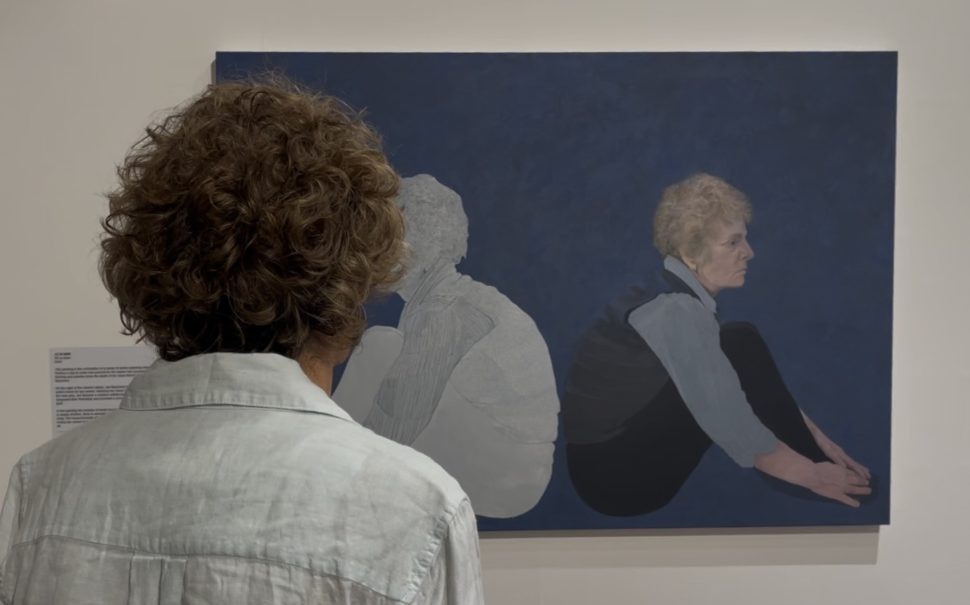 Artist Lucy ash admires her central portrait at the exhibition