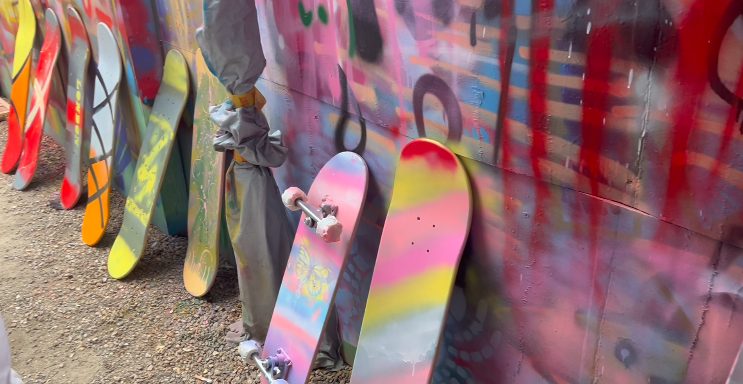 Graffiti painted skateboards lined up against wall.