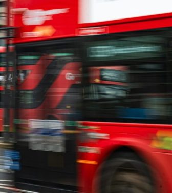 A blurry photo of red double decker buses driving down a road