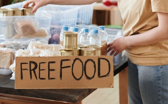 A picture of a person at a foodbank with a handwritten sign saying 'Free food'.