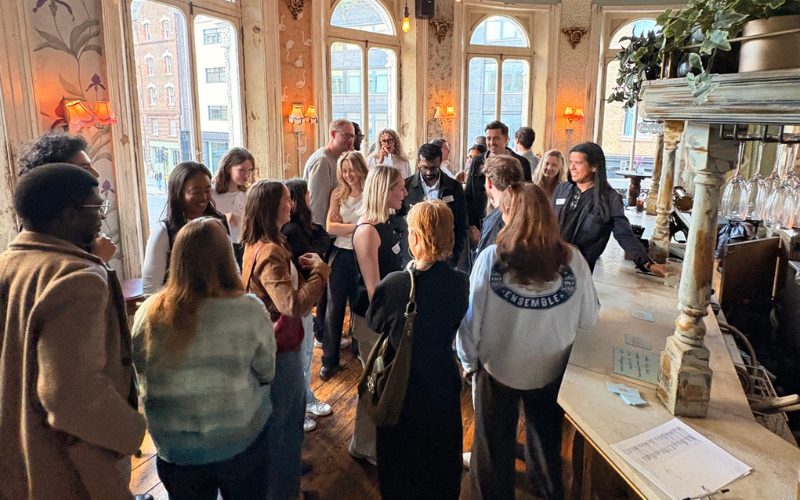 A group of strangers are standing in a pub at a small talk event socialising