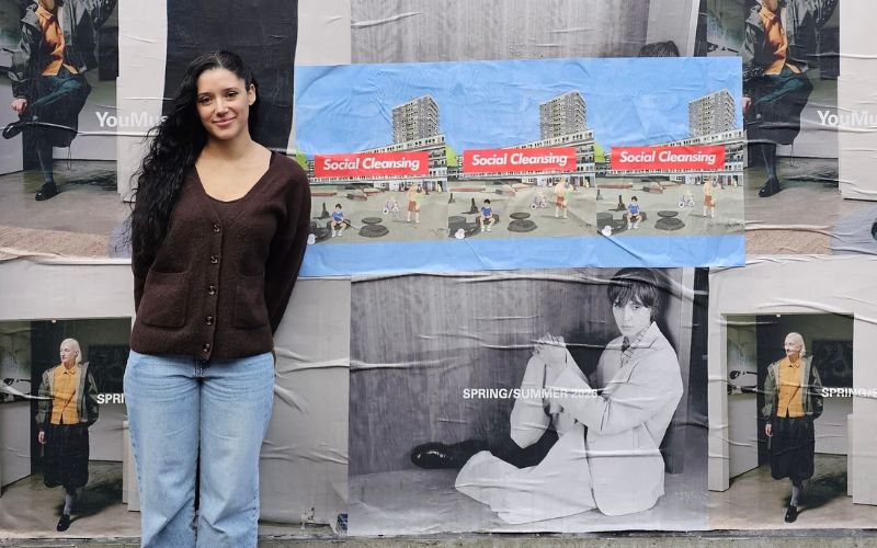 GG the Illustrator standing in front of her 'Social Cleansing' posters.