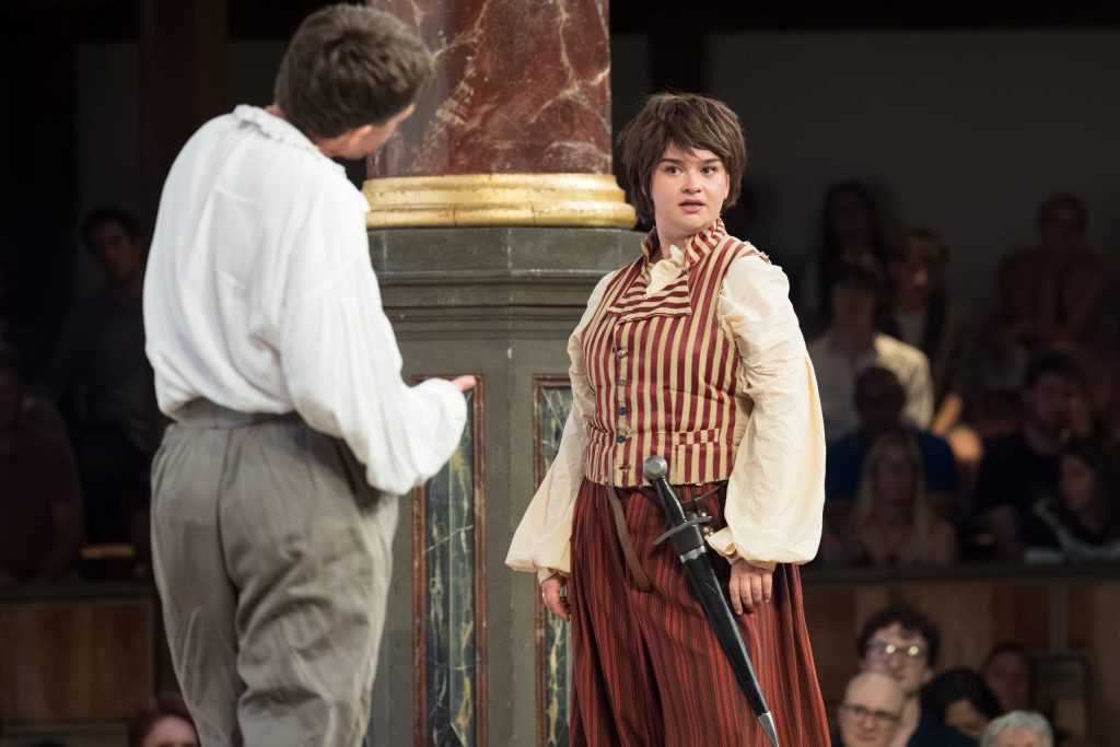 A pair face each other dressed in Shakespearean garb on the stage of Shakespeare's Globe.