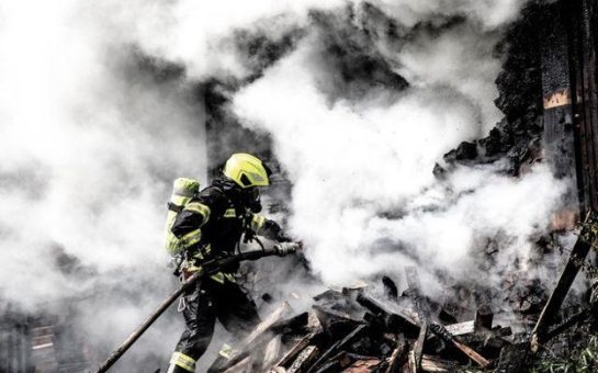 A firefighter tackling a fire, with smoke surrounding them.