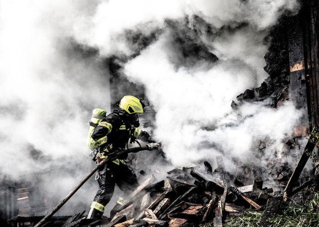 A firefighter tackling a fire, with smoke surrounding them.