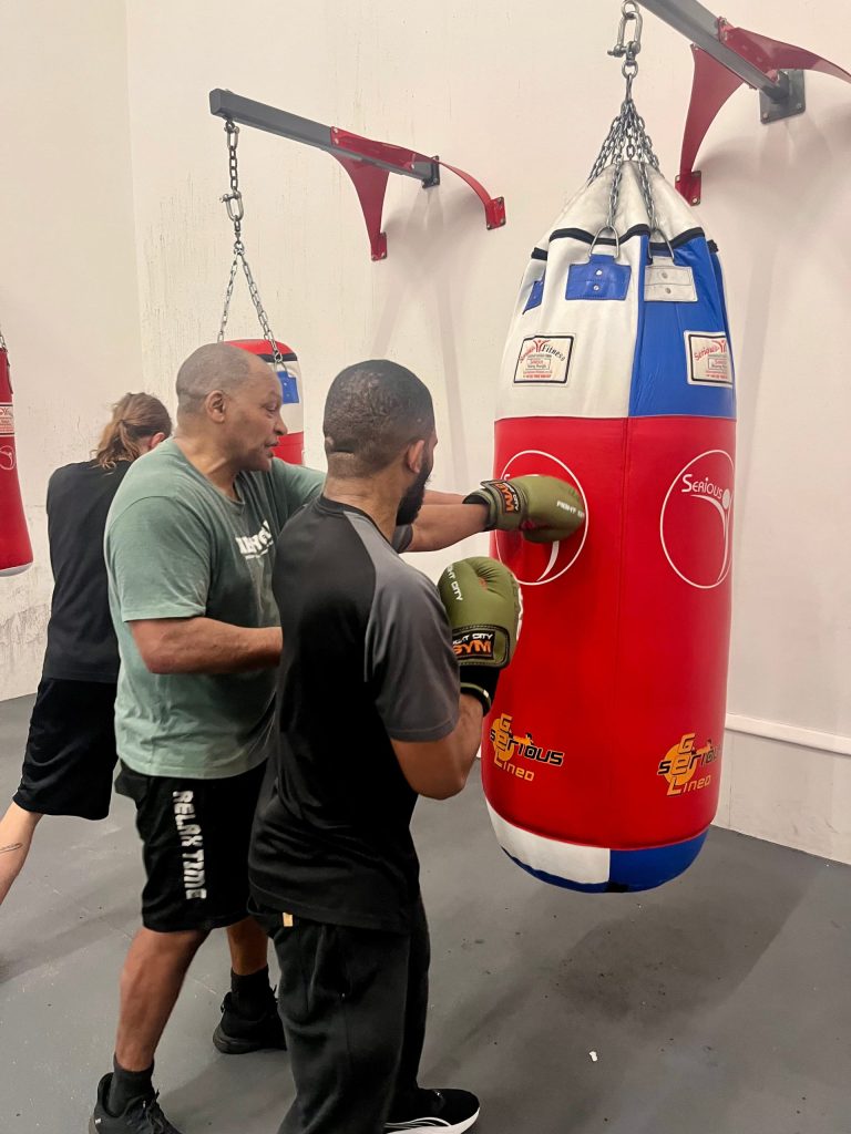 Coach Dennis Banton works with Andre Odom during a 'Box Fit' class.