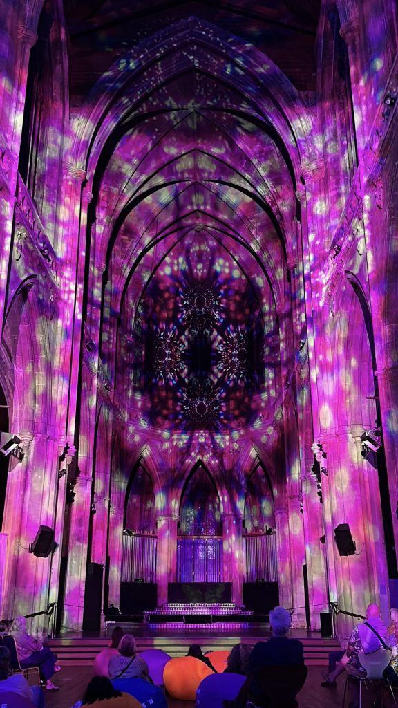 The church walls covered in a pink, purple and white kaleidoscope pattern that focuses in on the big end window.